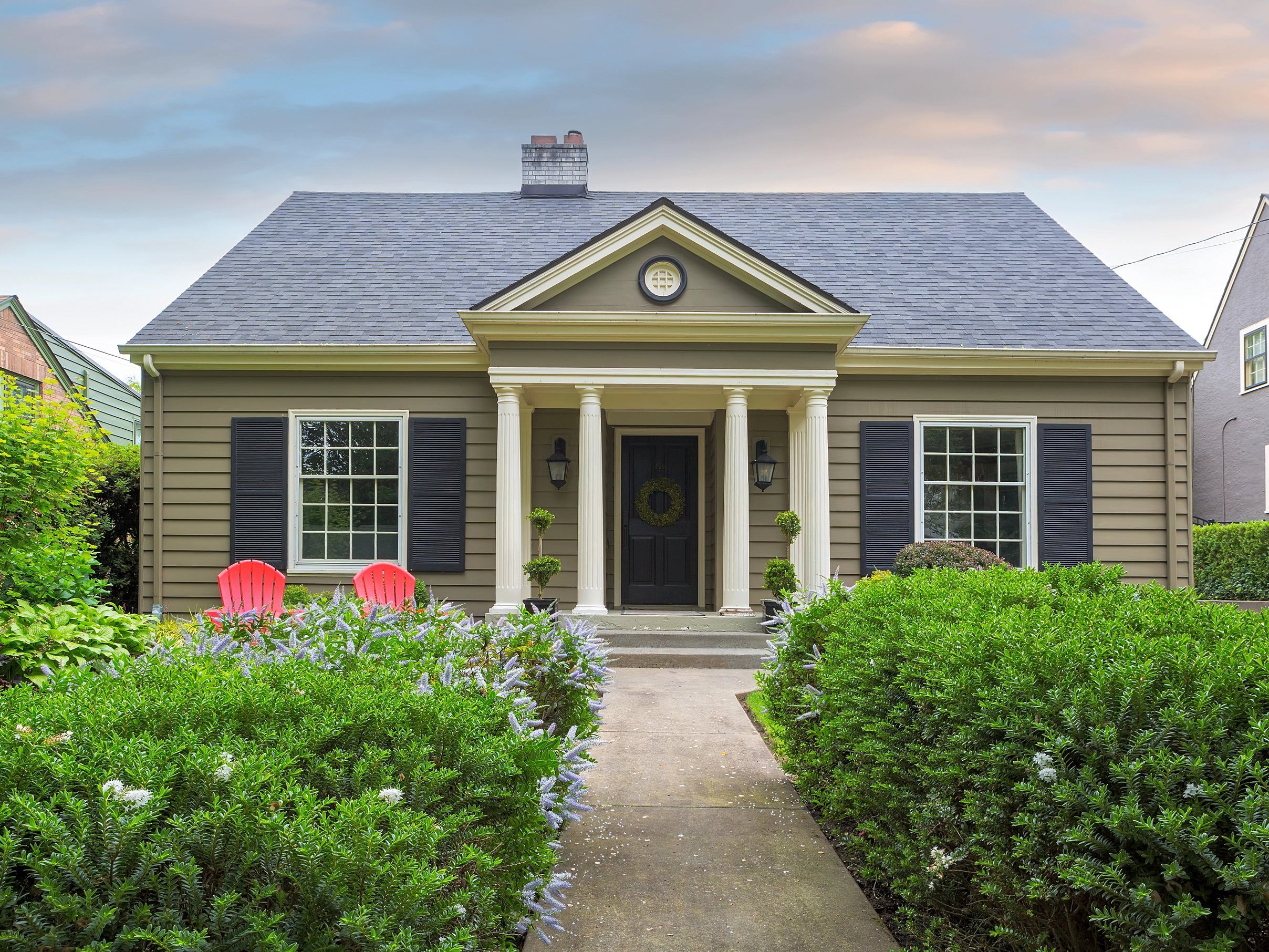 A tan Cape with a columned entry portico under a charcoal shingle roof.