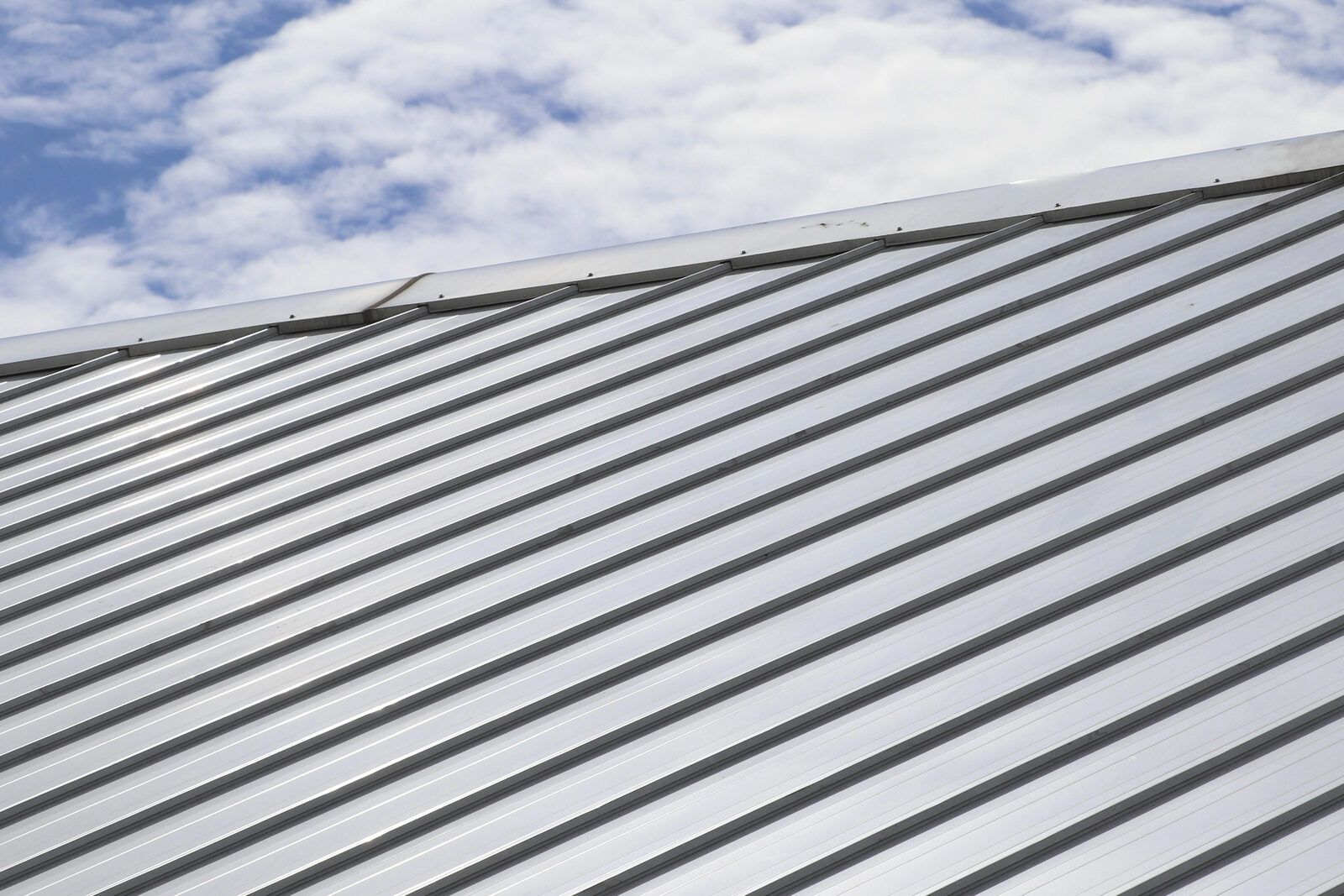 A silver metal roof with ribbed panels running up to a ridge cap.