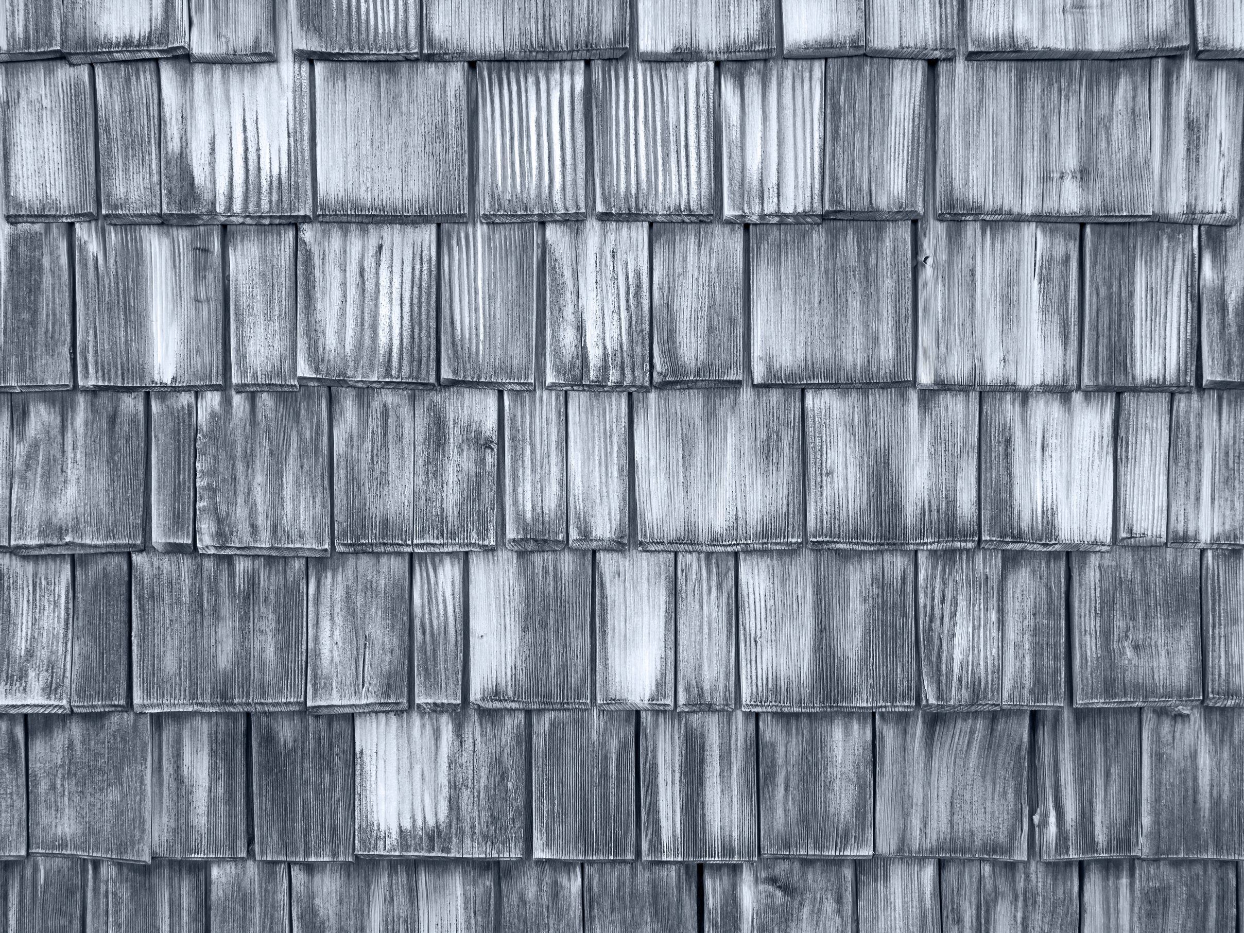Weathered grey cedar wall shingles, close up.