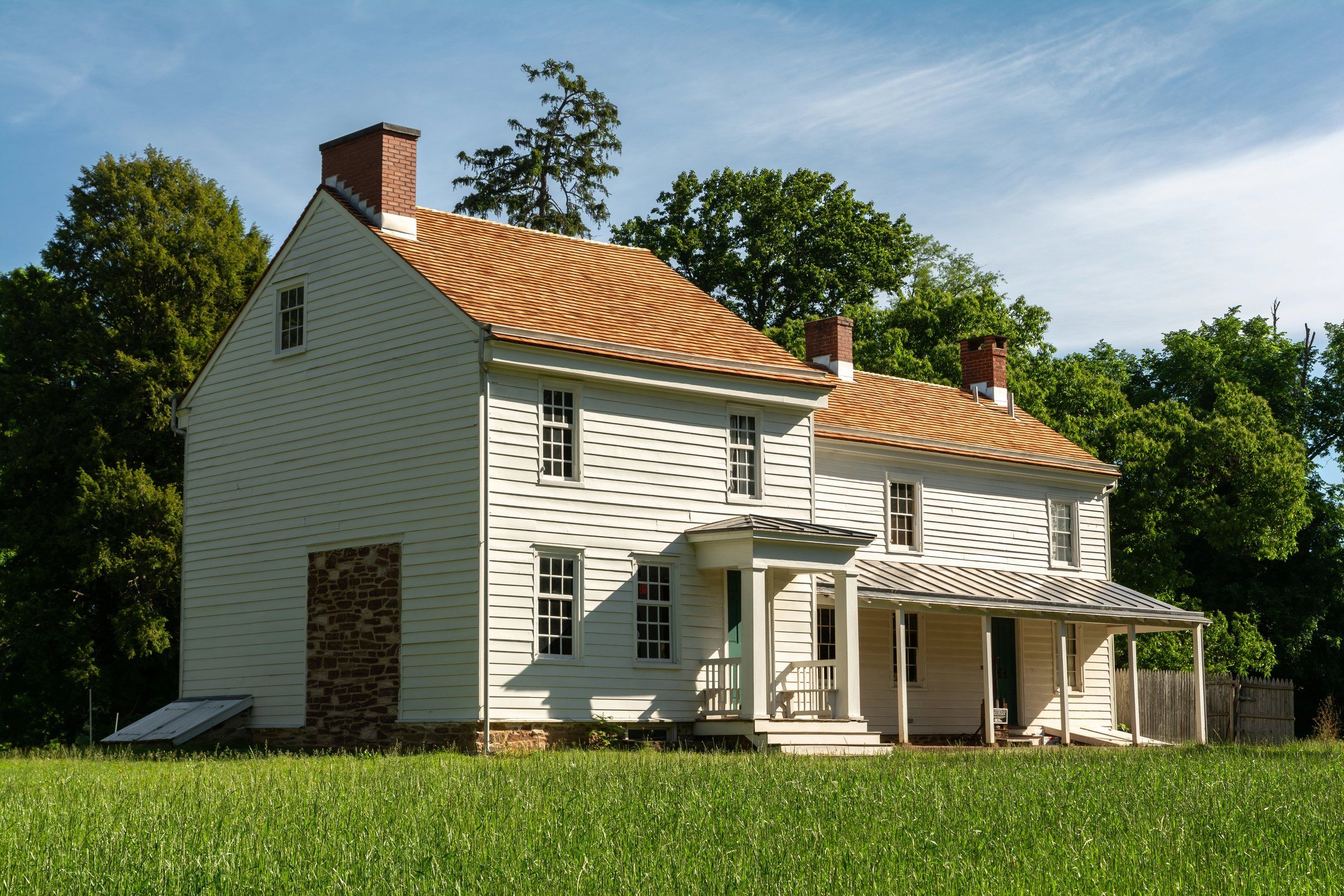 A white clapboard farmhouse with a new cedar-shake roof and three brick chimneys.