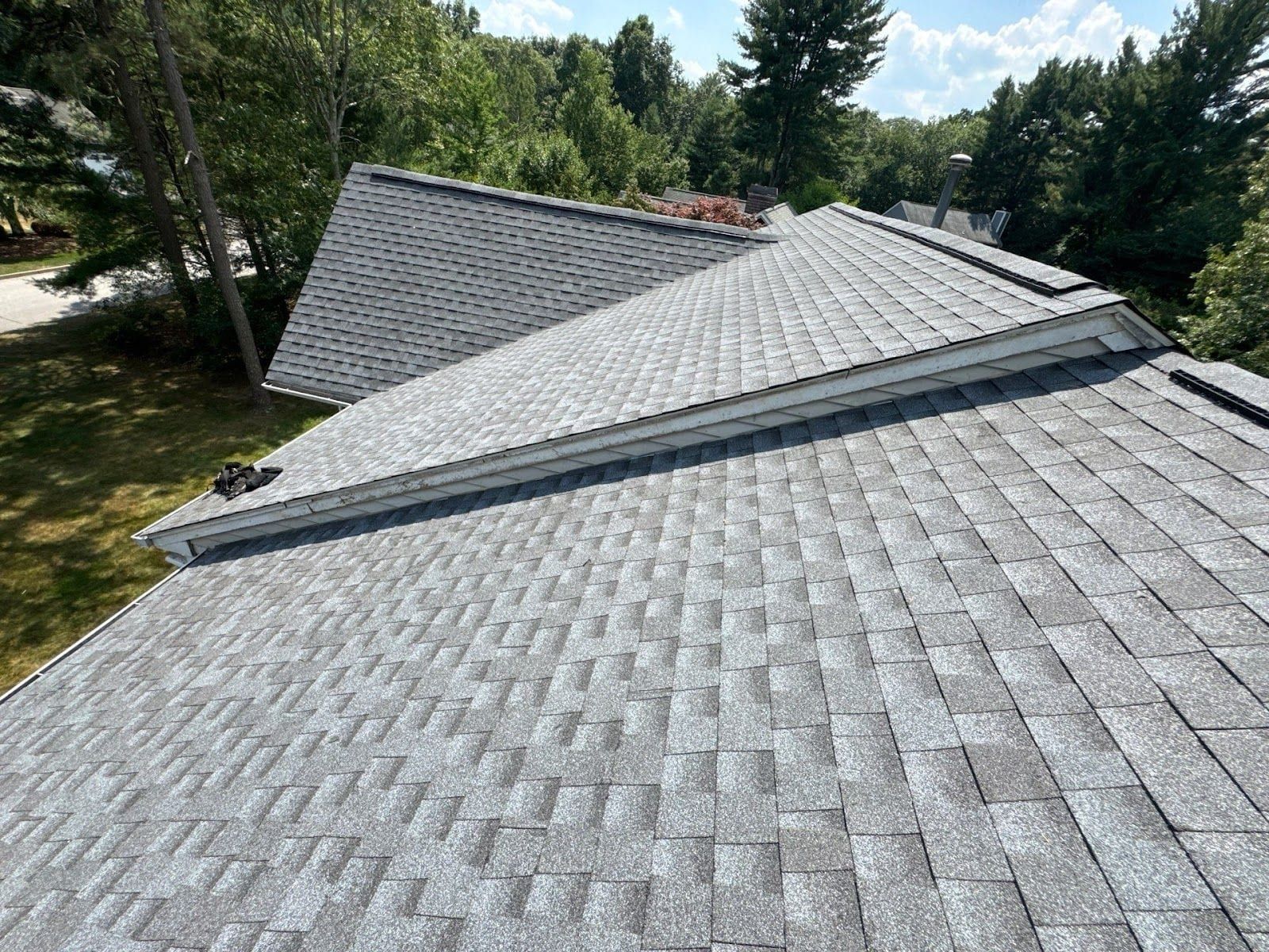 Elevated view across a finished grey architectural-shingle roof with several intersecting planes.