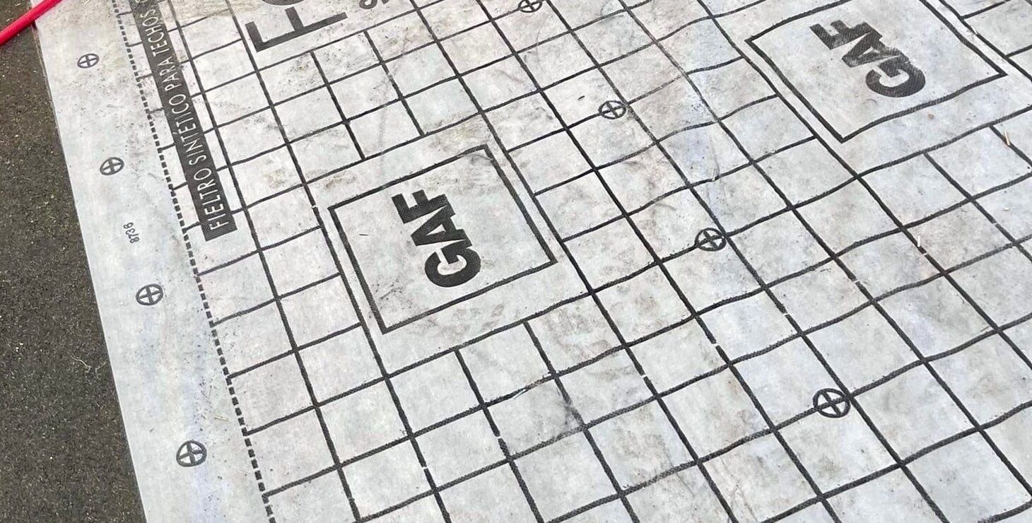 Printed synthetic roof underlayment with GAF marks laid over the roof deck.