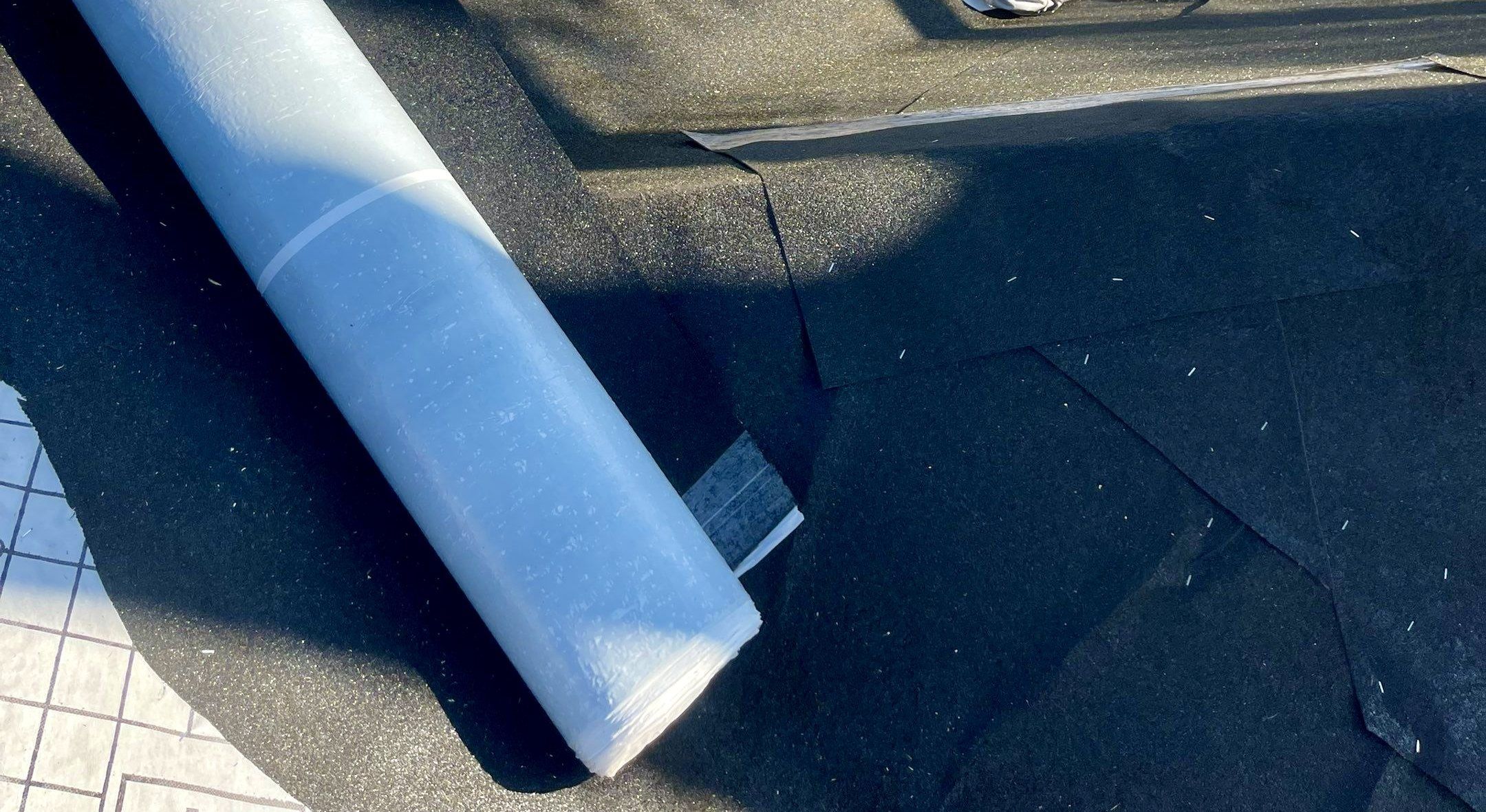 A roll of ice and water membrane on a roof dried in with black underlayment.